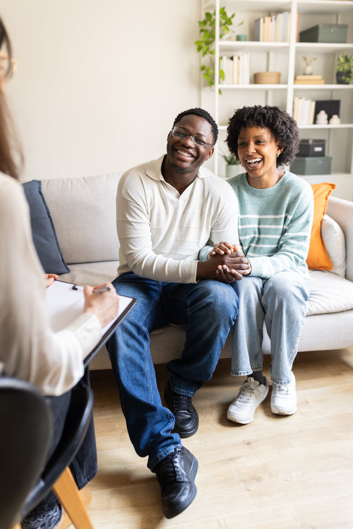 A couple holding hands while talking with their therapist
